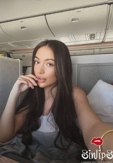 Felixa, stunningly beautiful Russian escort in London (South Kensington) with long brunette hair and brown eyes taking a selfie on plane