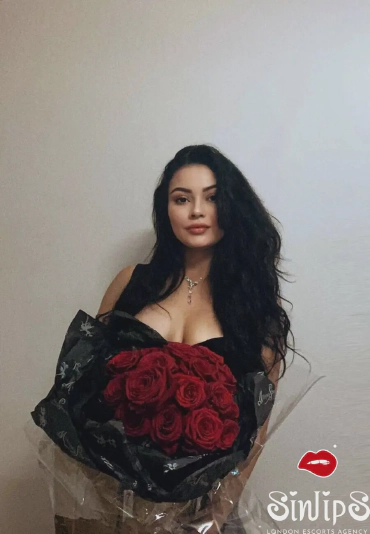 Kizzy, busty brunette escort in London in a portrait photo holding roses